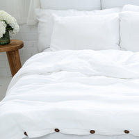 White organic pillow cases and duvet cover on a bed with a wooden side table and decorative elements.