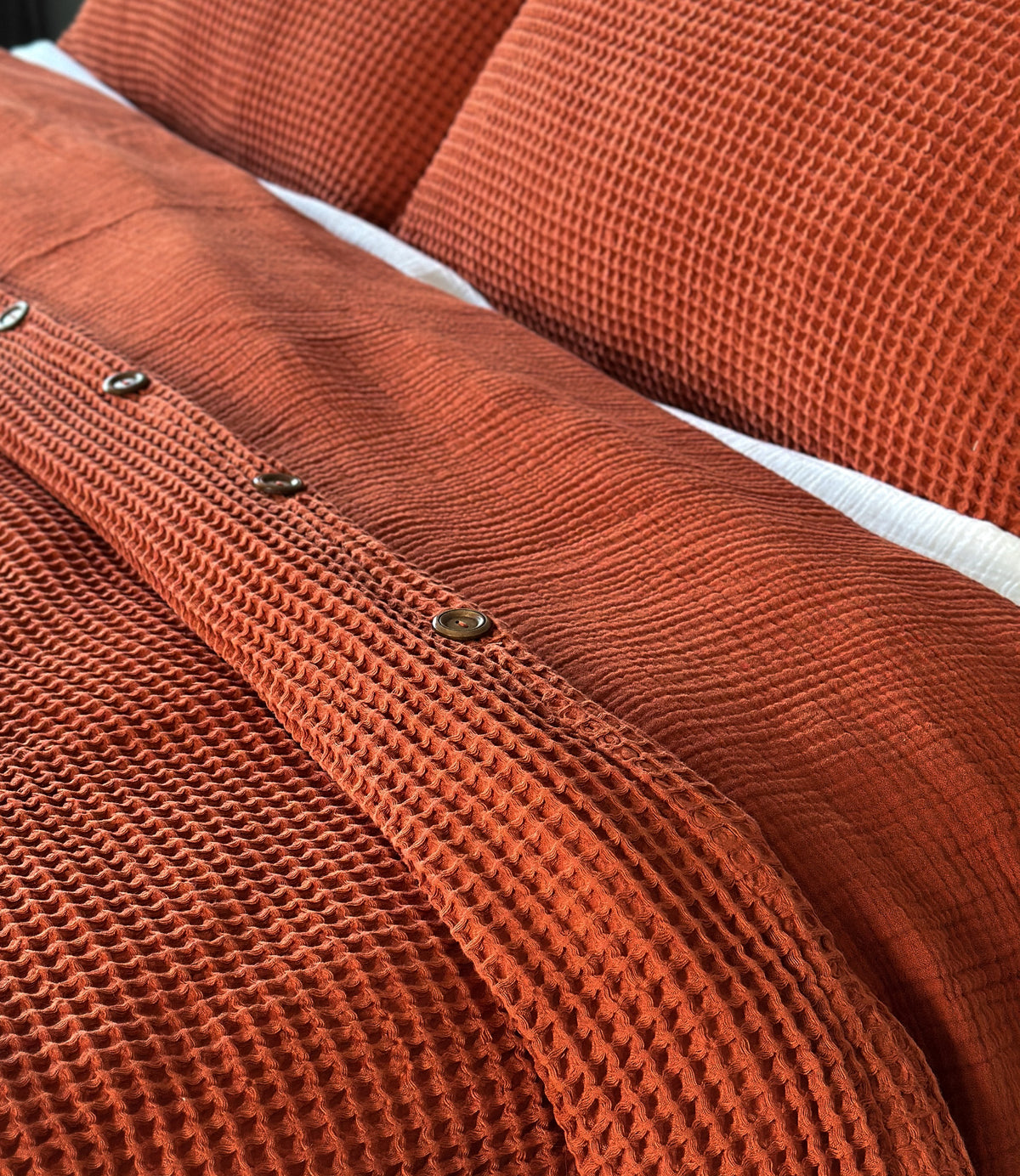 Close-up of a textured cinnamon duvet cover with buttons and pillow case set.