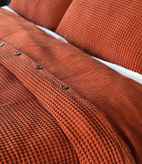 Close-up of a textured cinnamon duvet cover with buttons and pillow case set.