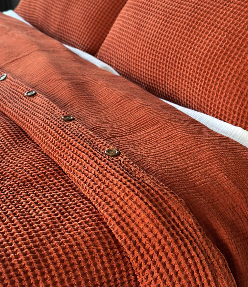 Close-up of a textured cinnamon duvet cover with buttons and pillow case set.