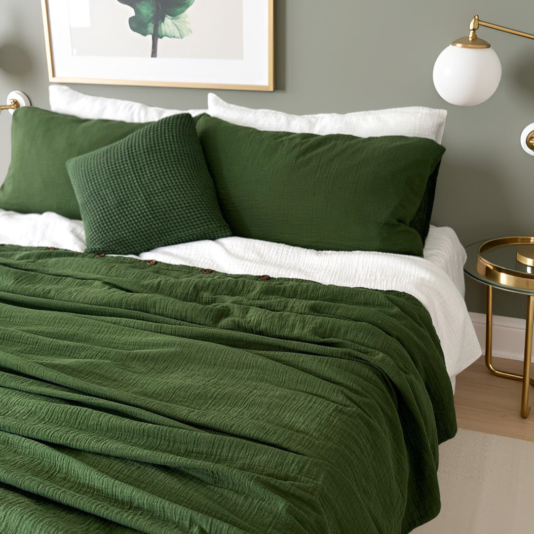 Green organic duvet cover bedding set on a bed with a side table and lamp in a bedroom setting.