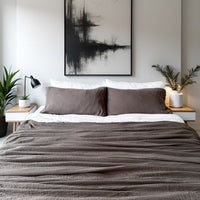 Modern bedroom with gray bedding, white walls, and abstract art.