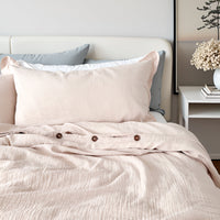 Neatly made bed with light beige bedding and pillows in a bedroom setting.