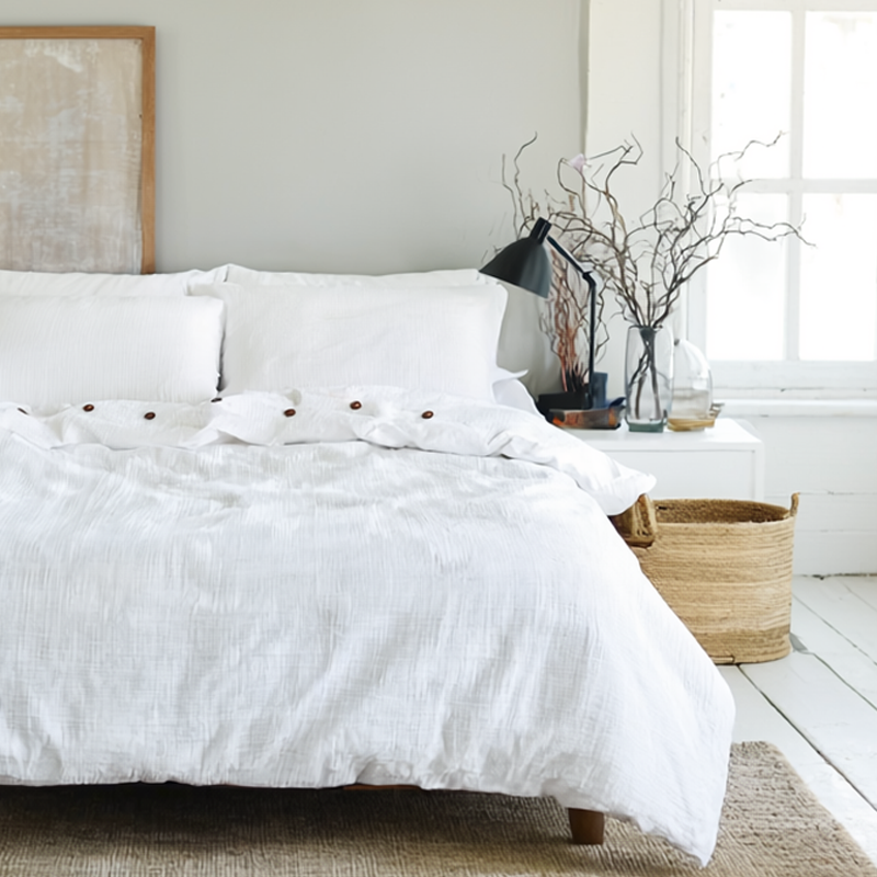 Neatly made bed with white bedding in a bright bedroom.